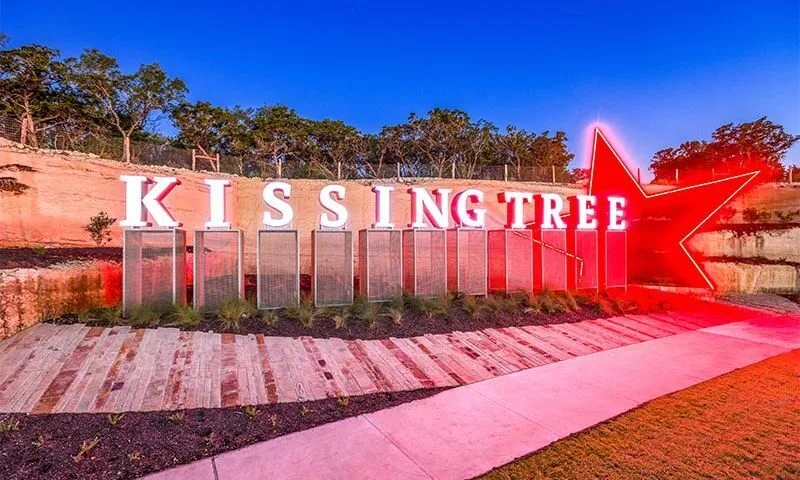 Large red star and white text reading KISSING TREE on a fence.