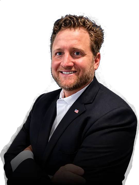 Man in a black suit with a white shirt and American flag pin on his lapel.
